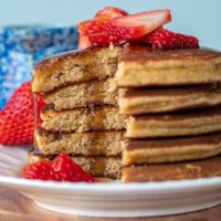 a stack of pancakes made with almond flour that are cut and syrup drizzling down