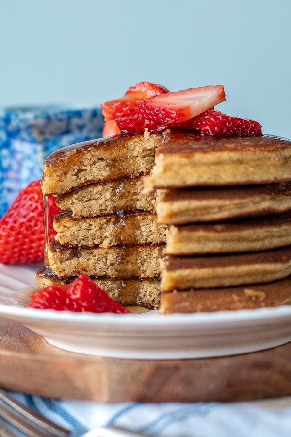a stack of pancakes made with almond flour that are cut and syrup drizzling down