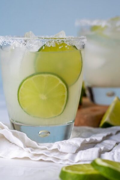 straight on shot of limeade margarita with lime slices next to it