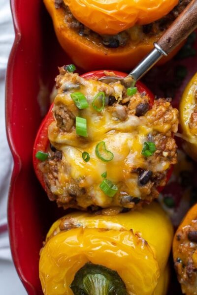 overhead shot of mexican stuffed peppers in a baking dish with a spoon going into one