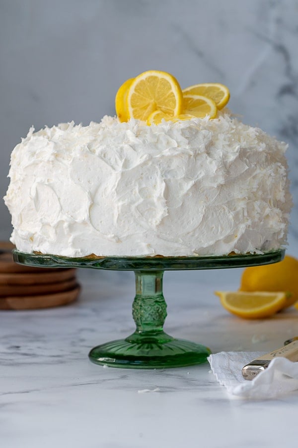 straight on shot of lemon coconut layer cake on a cake stand