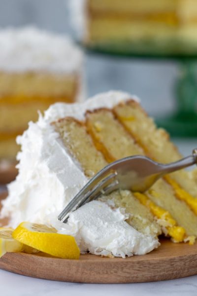 a fork cutting into slice of coconut cake with lemon filling