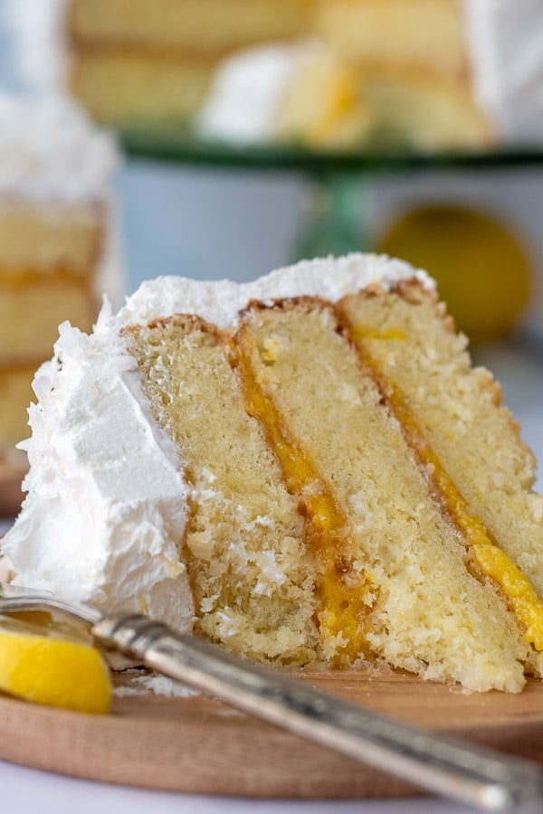 a slice of coconut cake with lemon curd filling with a bite taken out