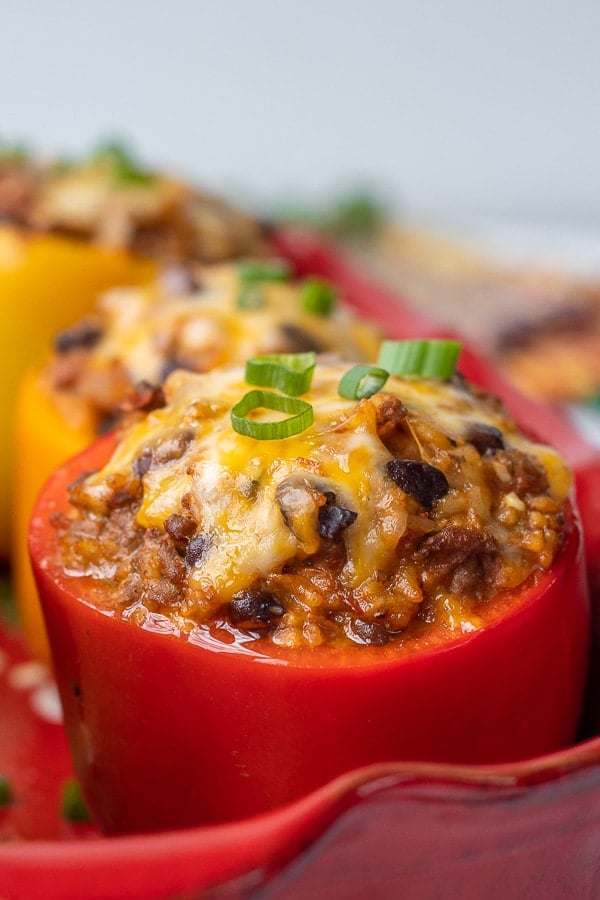 close up side angle of stuffed bell pepper in baking dish with melted cheese