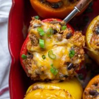 overhead shot of mexican stuffed peppers in a baking dish with a spoon going into one