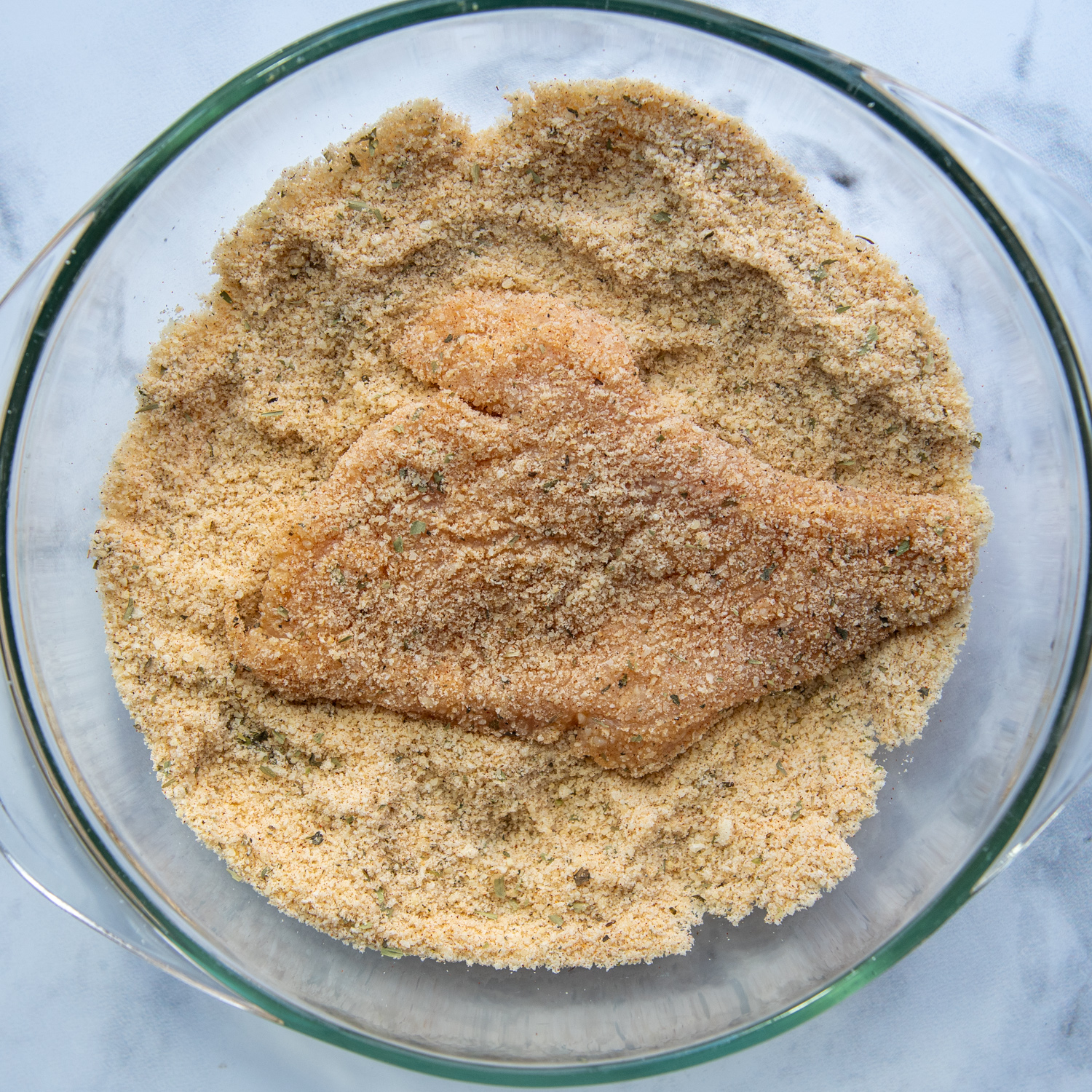 the chicken breaded in almond flour mixture in a bowl.