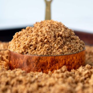 a heaping scoop of bread crumbs in a copper measuring cup