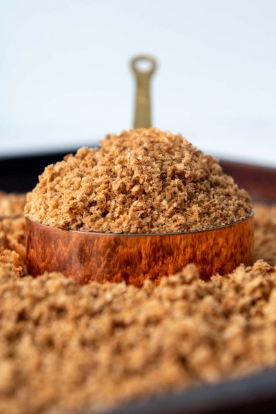 a heaping scoop of bread crumbs in a copper measuring cup
