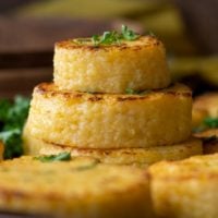 a stack of cheese grit cakes with fresh parsley sprinkled on