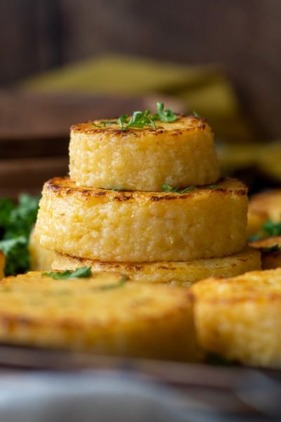 a stack of cheese grit cakes with fresh parsley sprinkled on