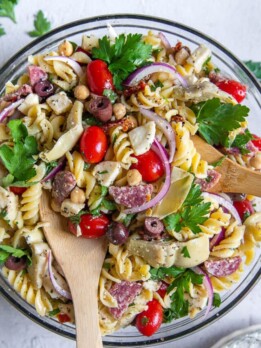overhead shot of cold pasta salad with wooden spoons sticking out of bowl