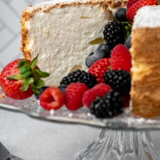 a sliced cake on a stand facing straight on with berries in the middle.