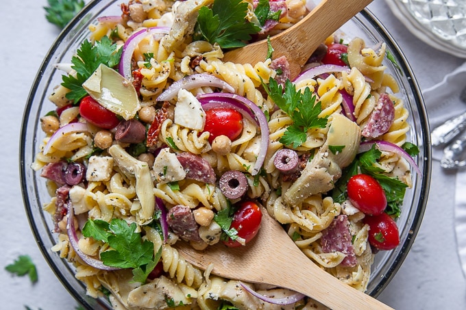 overhead shot of gluten free pasta salad with wooden spoons scooping up a serving