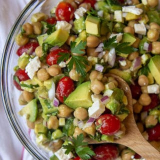 a wooden spoon holding up a serving of chickpea avocado salad