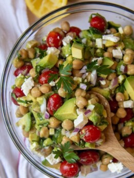 a wooden spoon holding up a serving of chickpea avocado salad