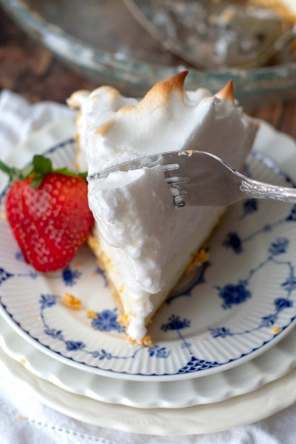 a fork slicing into the meringue on top of the frozen lemon pie