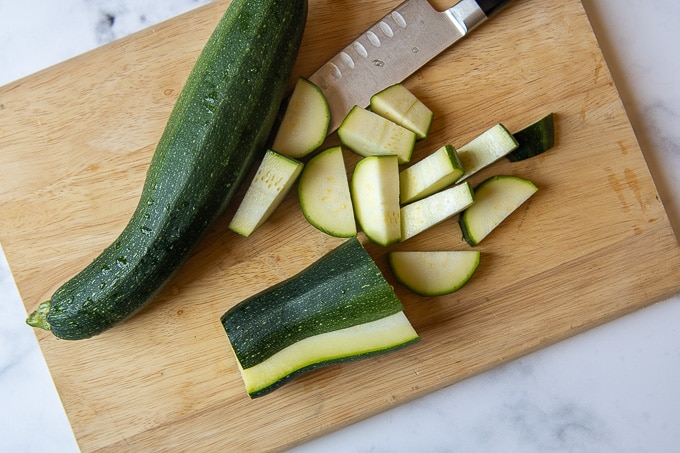 an image of zucchini being cut on a wooden cutting board
