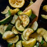 close up shot of cooked zucchini being held by a wooden spoon
