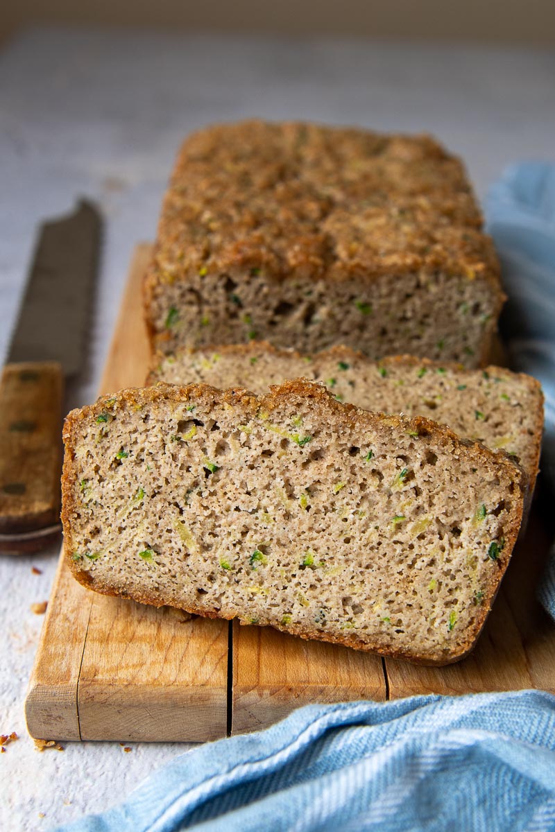a slice of almond flour zucchini bread sliced and propped up against the loaf