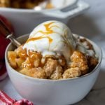 a bowl of apple crisp with ice cream and caramel on top