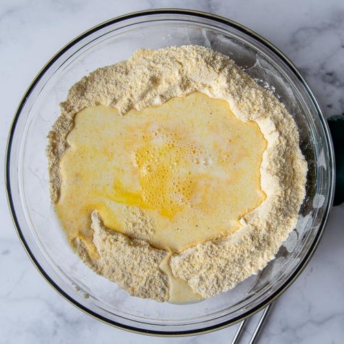 bowl of cornbread batter with milk and eggs