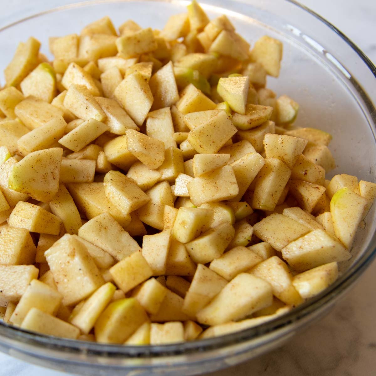 cut apples in a bowl with sugar, spices and cinnamon.