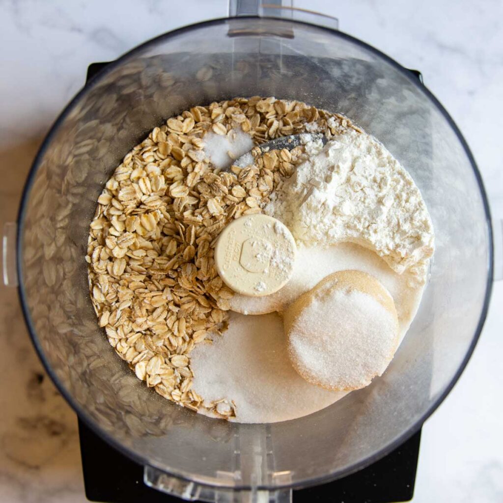 a food processor with oats and other dry ingredients.