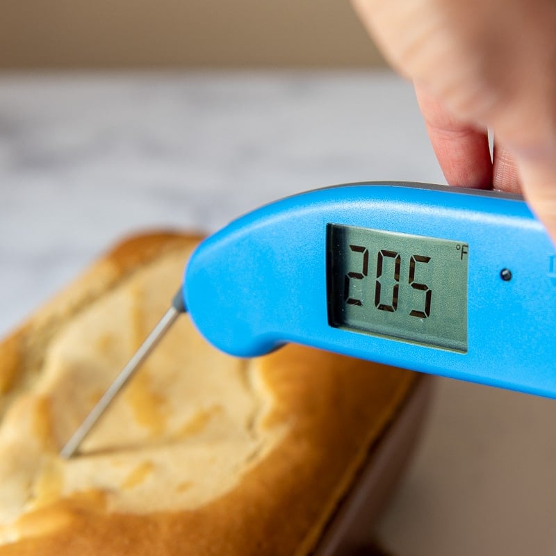 a thermometer going into a loaf of bread