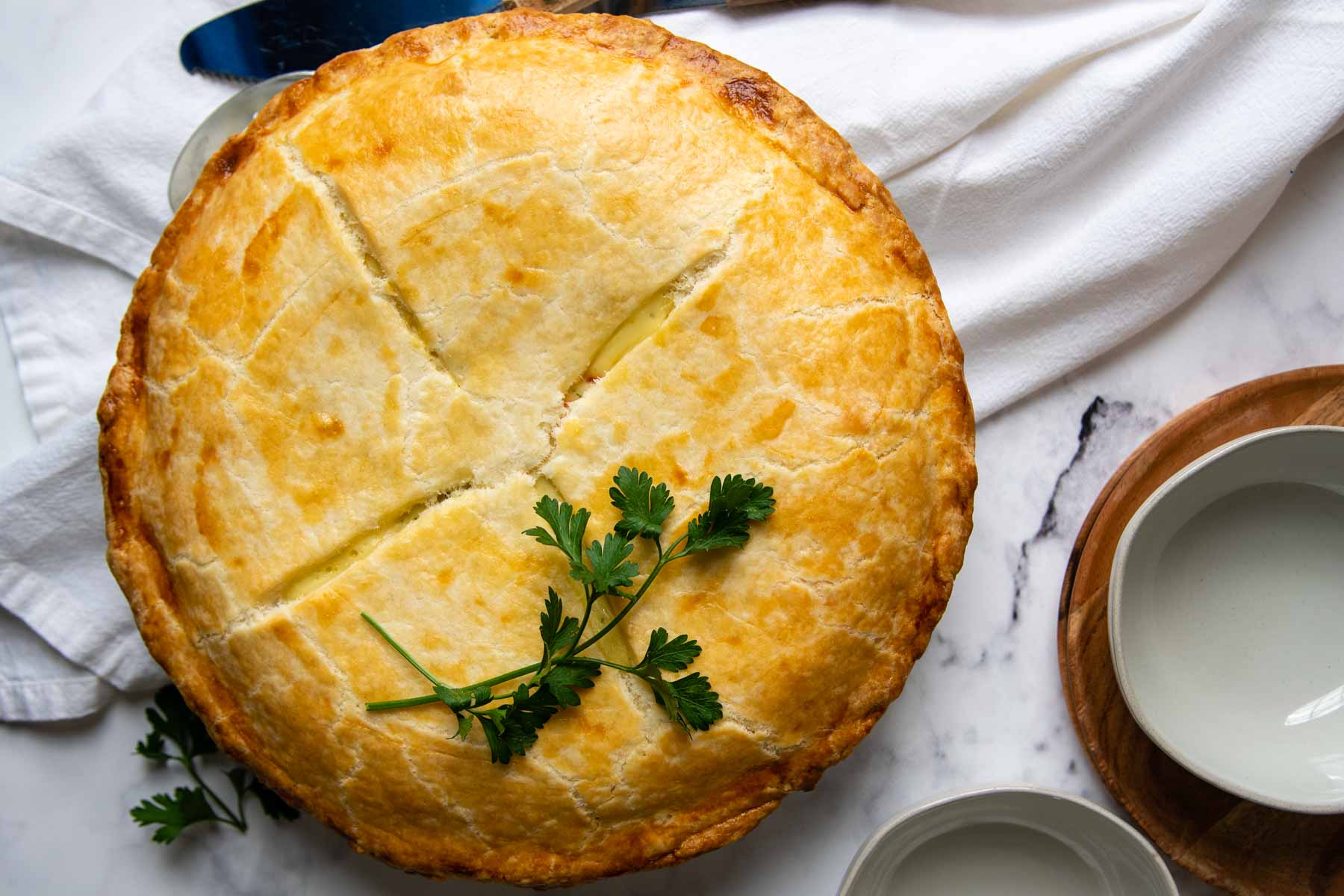 assembled uncut baked pot pie with fresh parsley on top