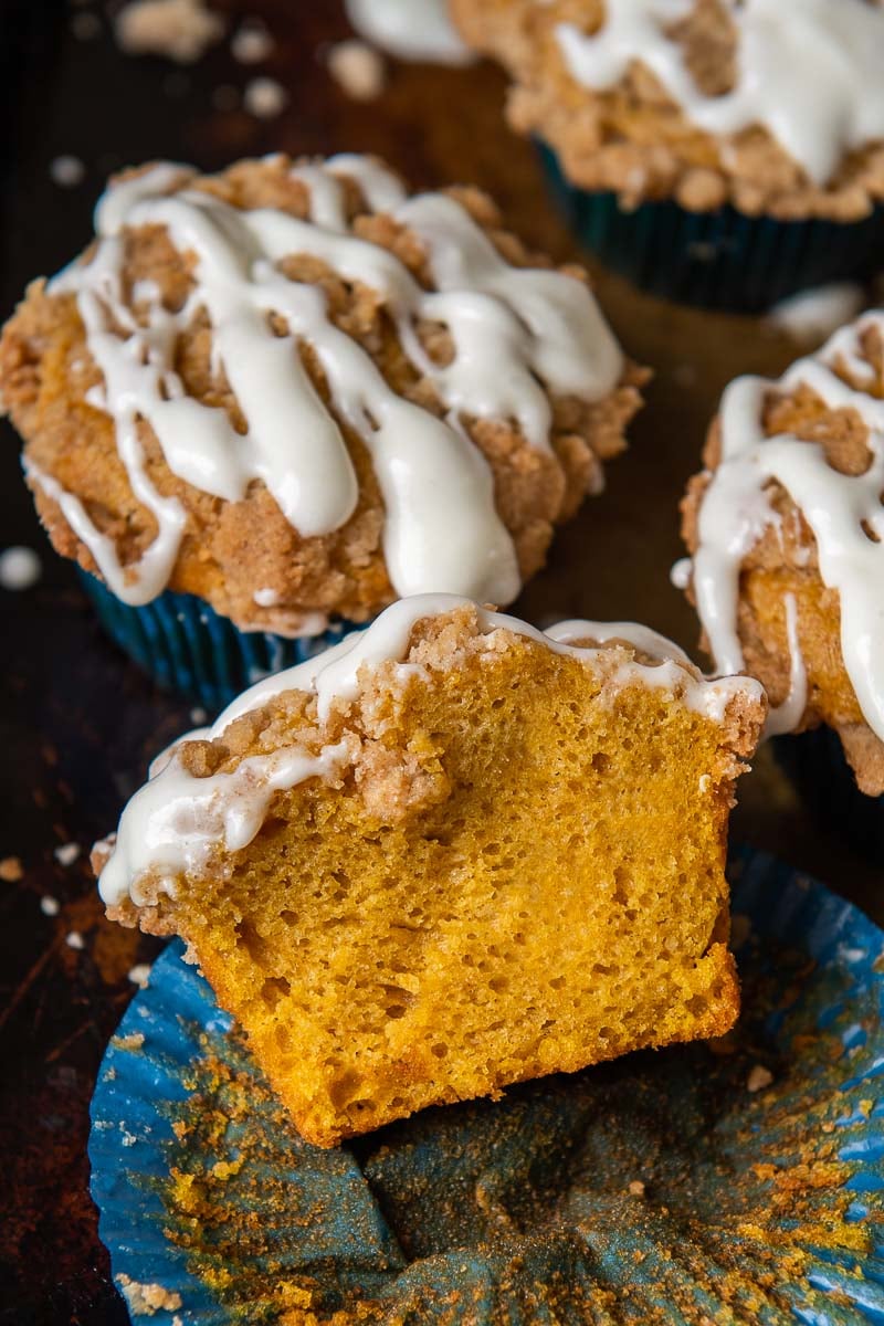 a pumpkin muffin split open and resting on a muffin liner