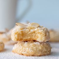 a stack of two almond paste cookies with the top one having a bite taken out