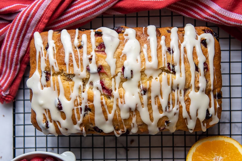 overhead shot of unsliced cranberry orange bread with a glaze drizzled on
