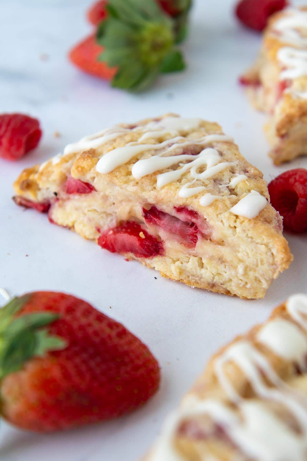 a berry scone on a white surface with strawberries around