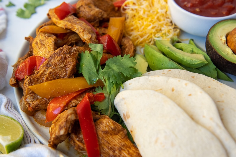close up of chicken fajita meat on a plate with fixings