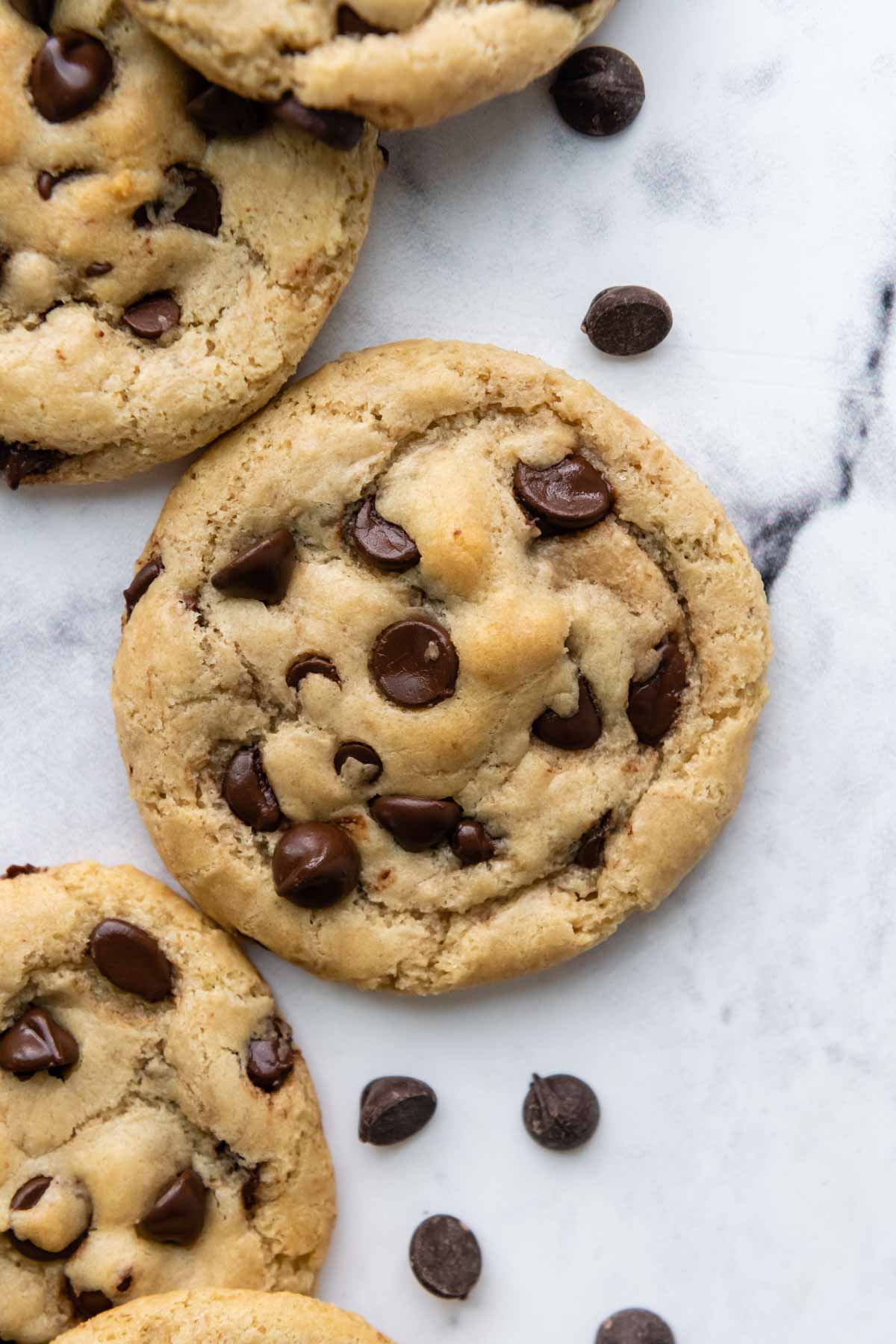 overhead shot of chocolate chip cookies with chocolate chips next to them.