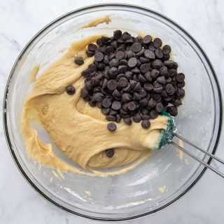 chocolate chips being mixed into cookie dough