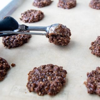 a cookie scoop putting no bake cookies on a baking sheet
