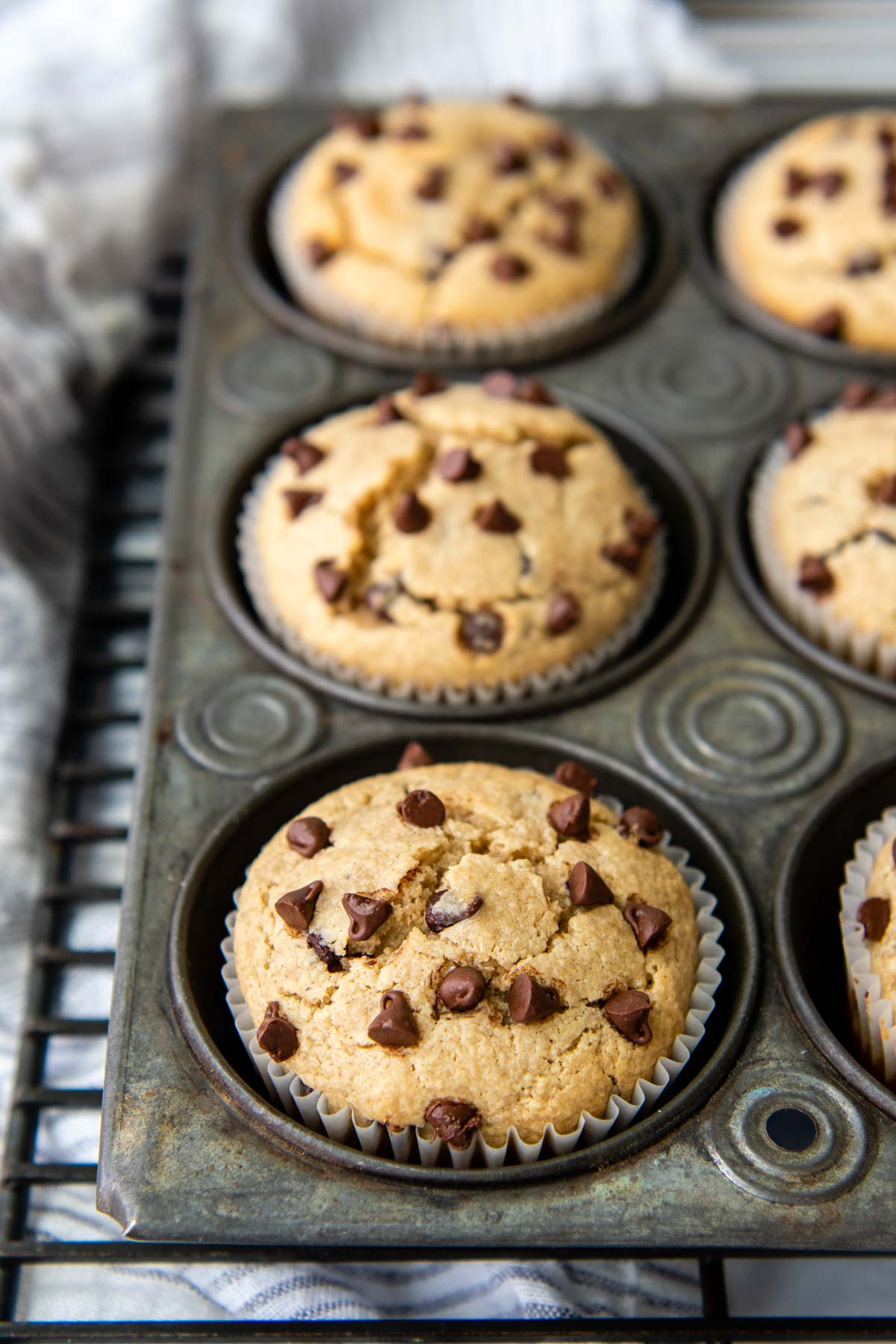 a muffin pan filled with chocolate chip almond flour muffins on a cooling rack.