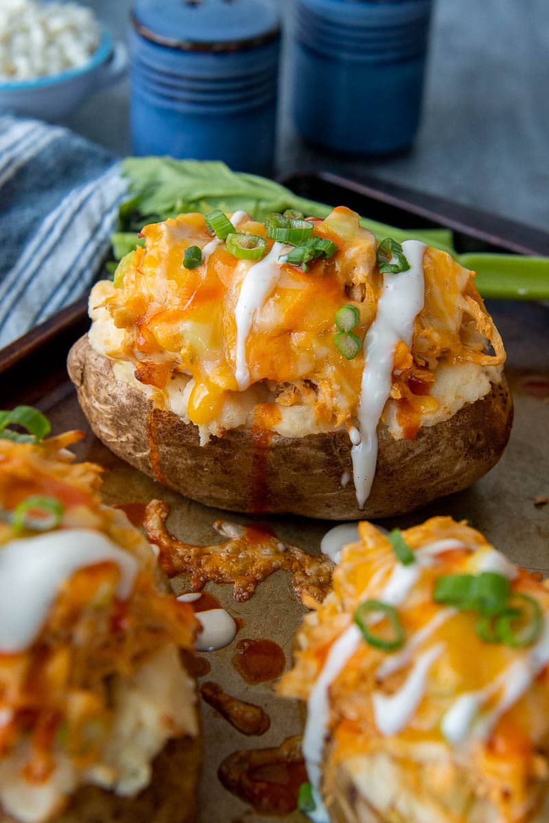 a buffalo chicken baked potato with ranch dressing drizzled over top