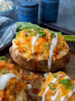 a buffalo chicken baked potato with ranch dressing drizzled over top