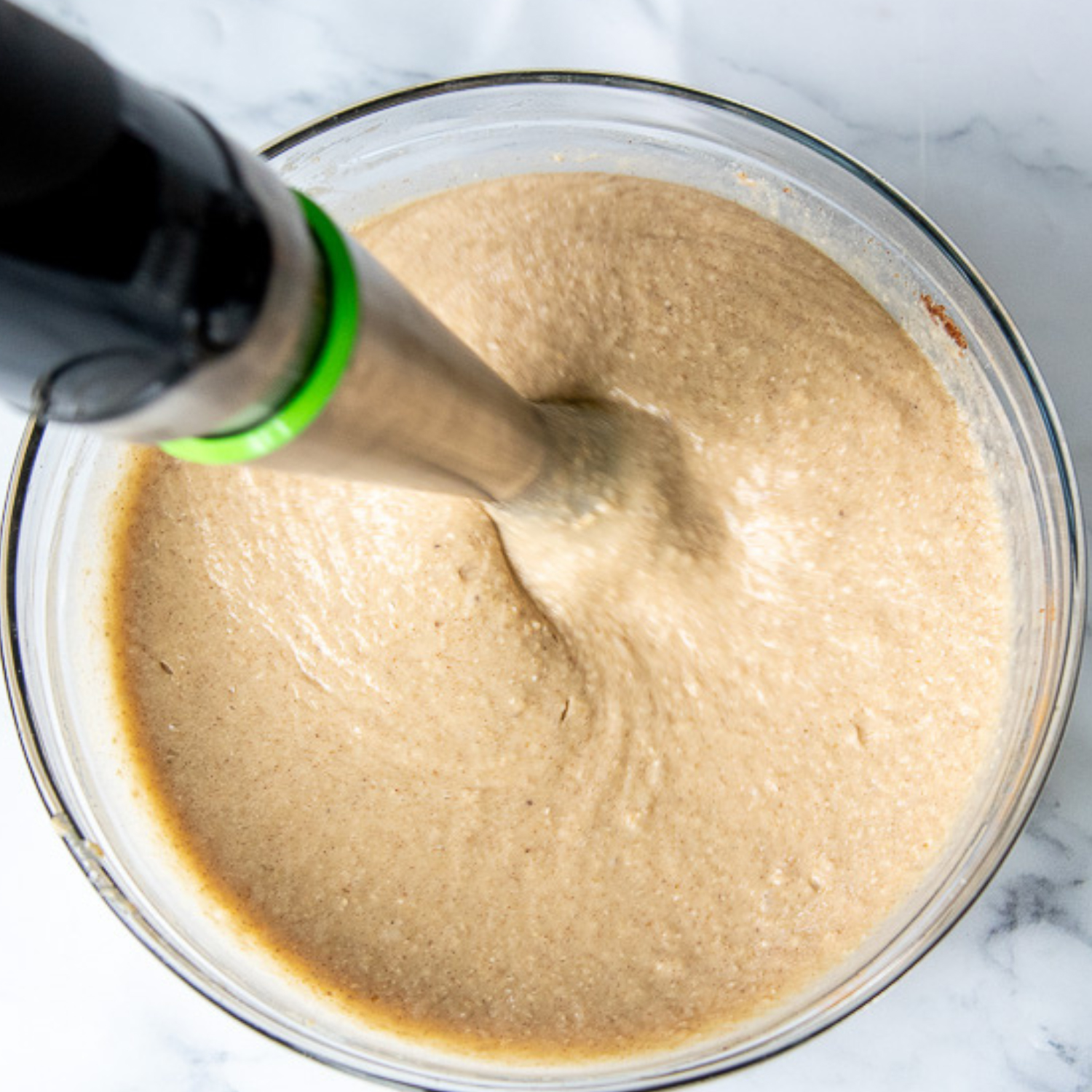 an immersion blender mixing the batter.