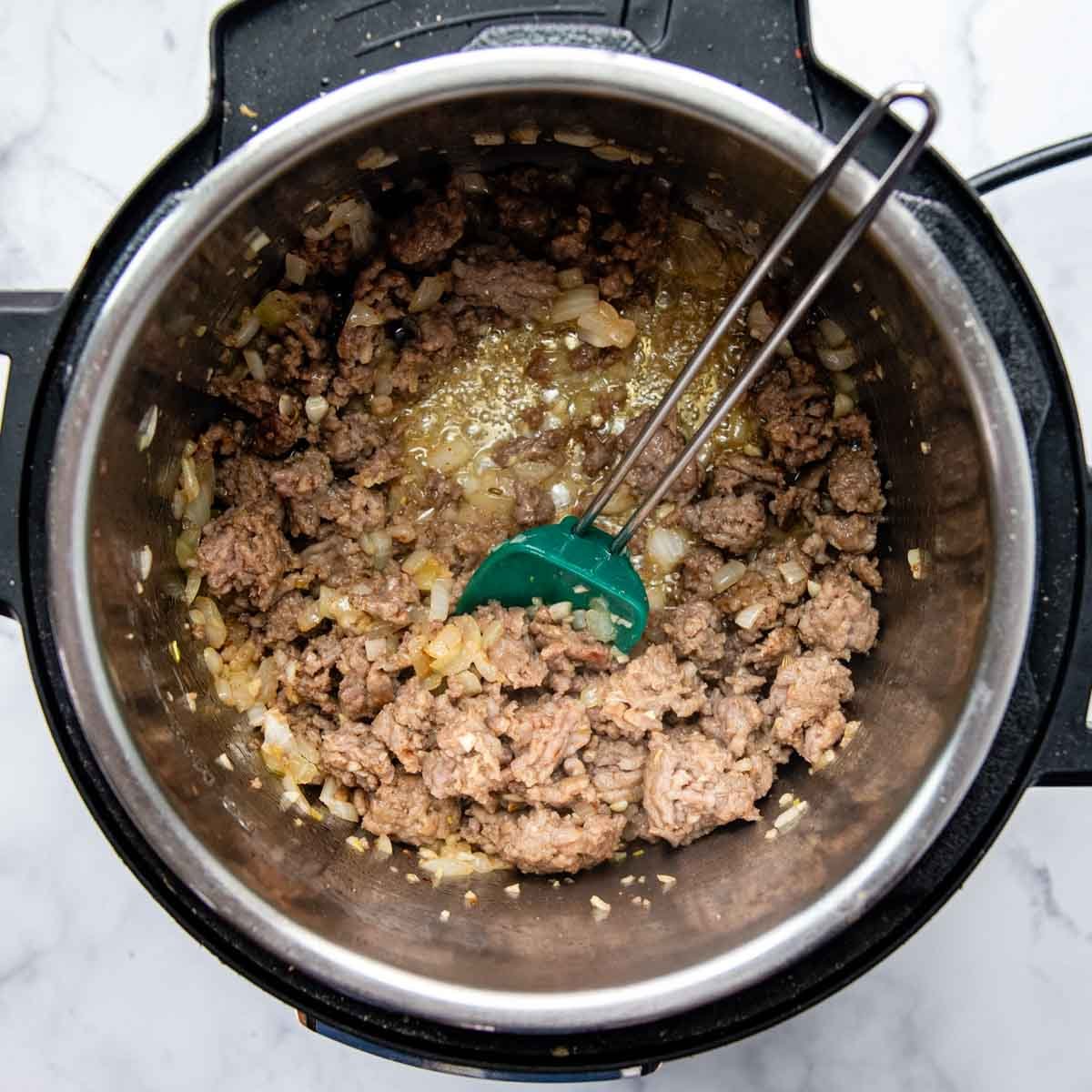 sausage, onions, and garlic cooking in the pressure cooker.
