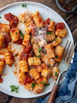 overhead shot of gnocchi on a white plate with a fork resting on it