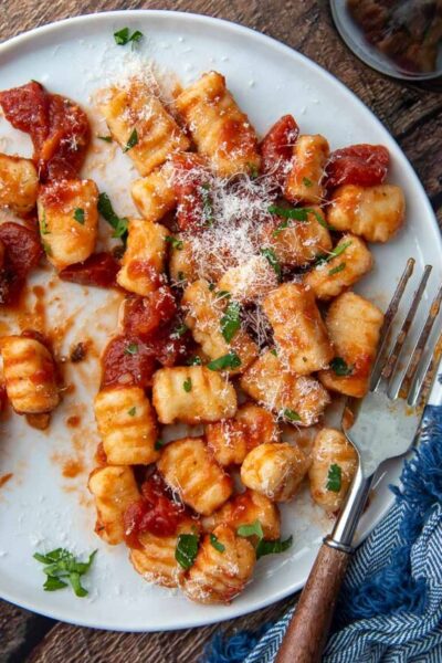 overhead shot of gnocchi on a white plate with a fork resting on it
