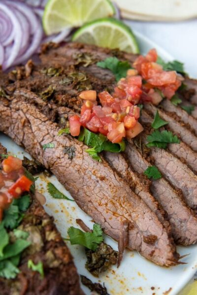 sliced flank steak on a plate with pico over top