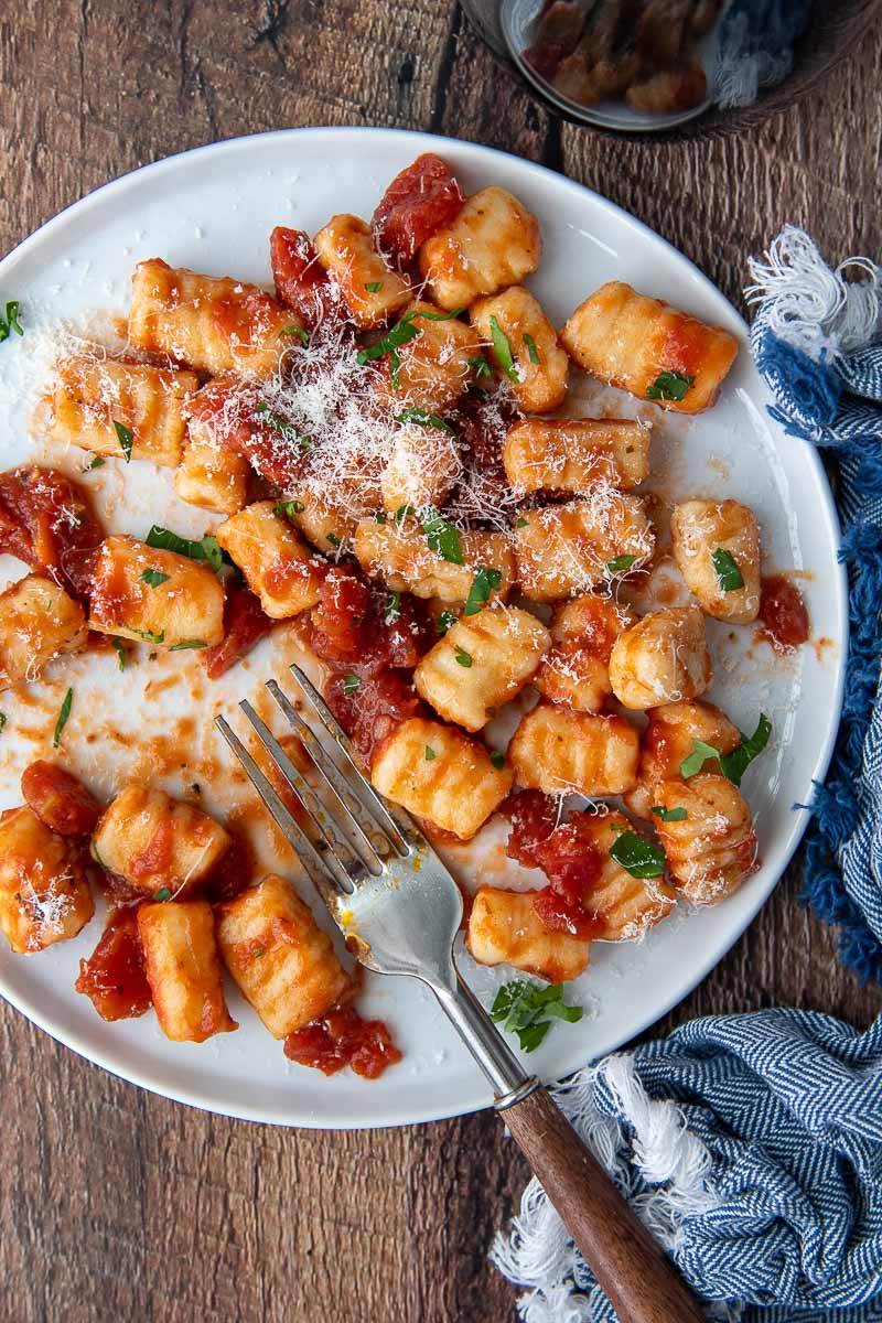 overhead shot of gluten free gnocchi on a white plate with red sauce