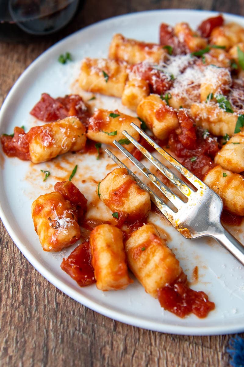 close up of a fork resting on a plate with gnocchi