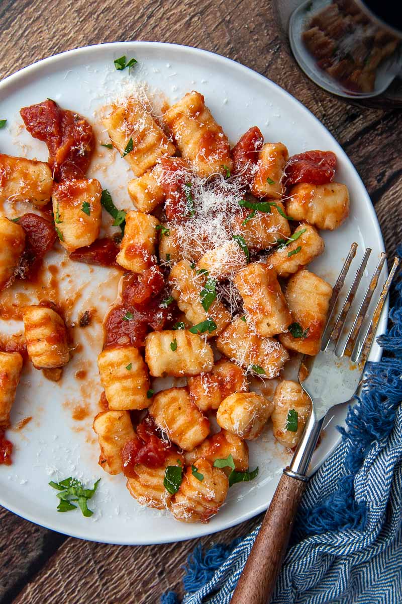 overhead shot of gnocchi on a white plate with a fork resting on it