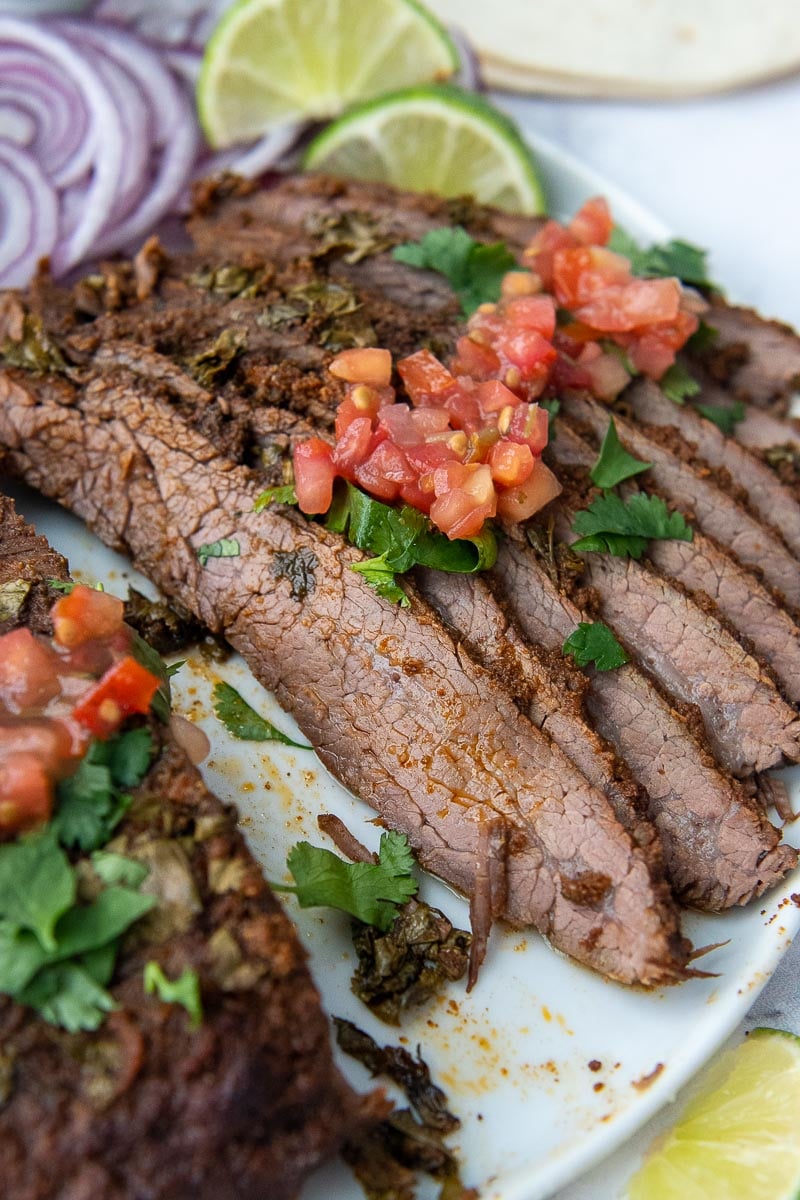 sliced flank steak on a plate with pico over top