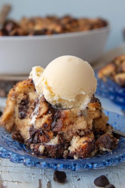 another shot of a serving of chocolate chip bread pudding on a blue plate with a scoop of melting ice cream on top